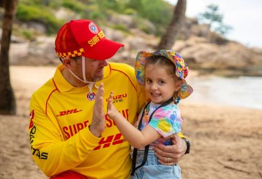 Surf lifesaver holding child on the beach